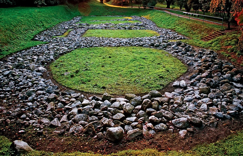 Fundamenty pałacu książęcego w Grodzie w Gieczu, na tle trawy widoczny zarys palatium, w którym dominują kamienie 