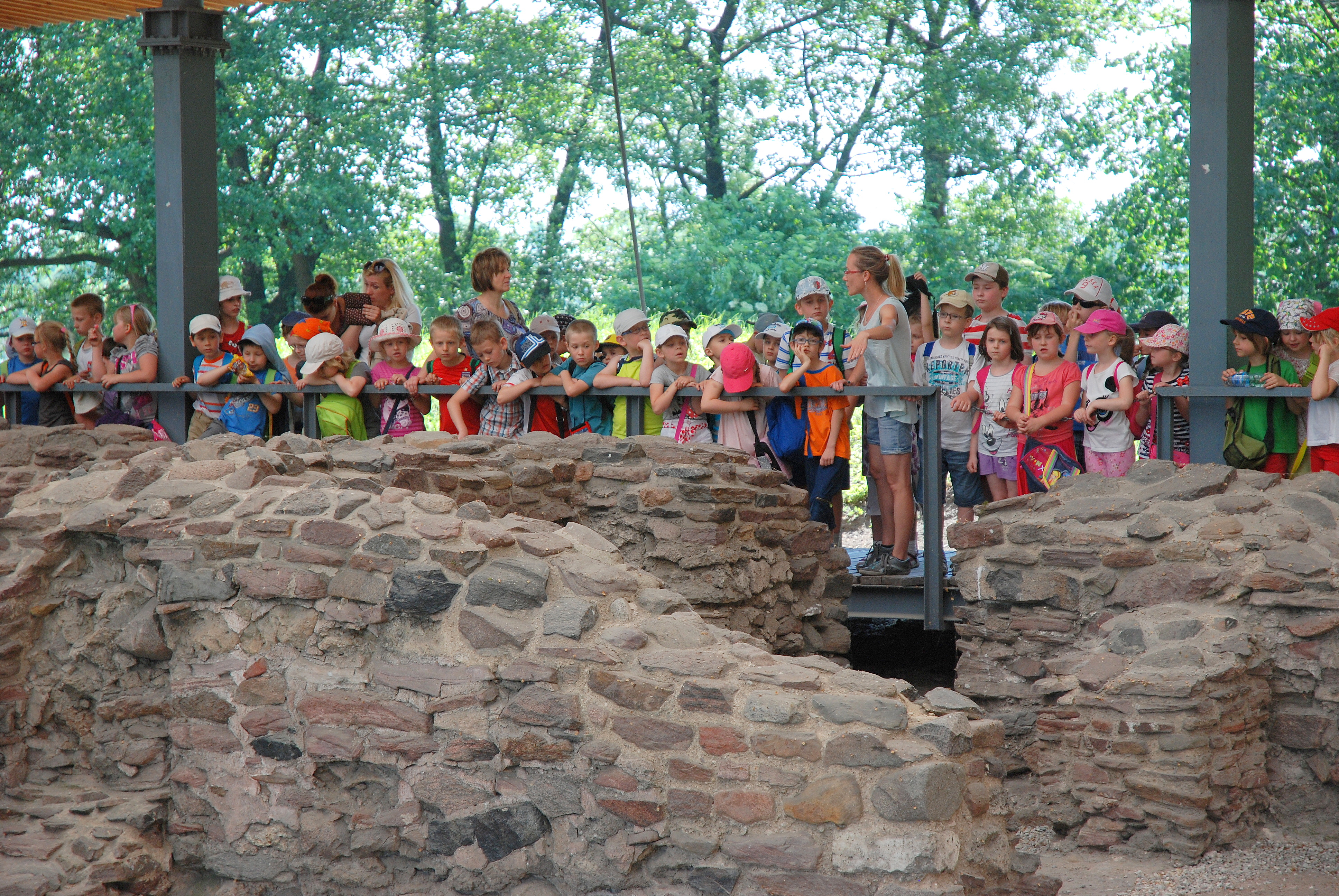 grupa dzieci z przewodnikiem z Muzeum podczas oprowadzania po ruinach palatium