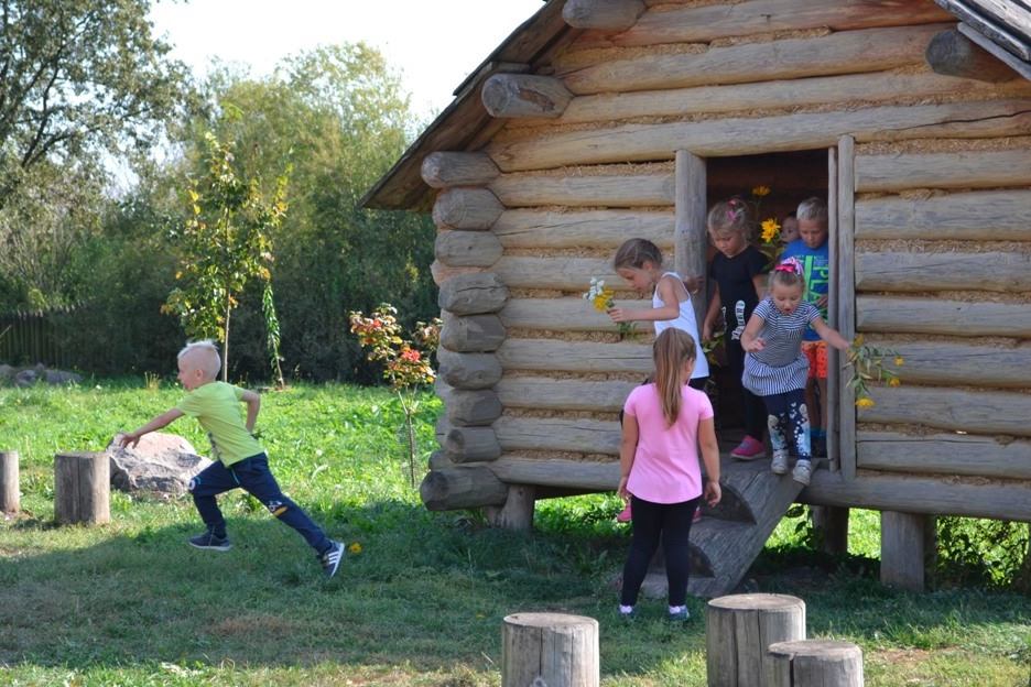 Dzieci wychodzące z drewnianego budynku 