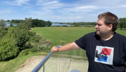 Na pierwszym planie Mateusz Wawrzyniak - archeolog. W tle Ostrów Lednicki