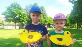 Dwóch chłopców w skansenie prezentujących swoje prace, dwie żółe tekturowe kaczuszki.