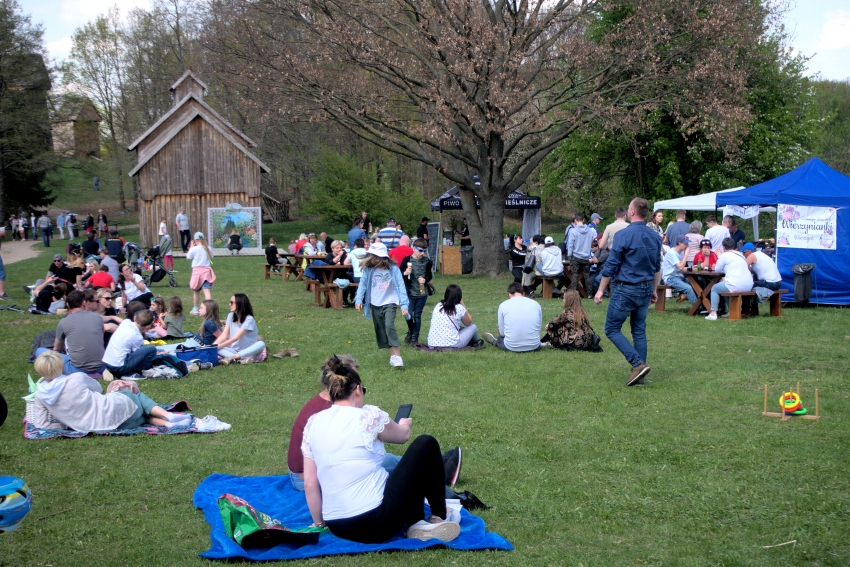 Turyści siedzący na kocach na zielonej trawie w parku. 