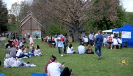 Turyści siedzący na kocach na zielonej trawie w parku. 
