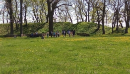 Zielona trawa, grupka uczestników przy tarczy do  strzelania z łuku. 