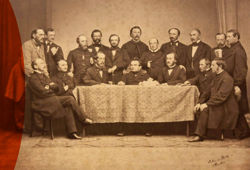 Stara fotografia; zebranie Koła Polskiego na sejm pruski, 18 mężczyzn gromadzi się przy stole.