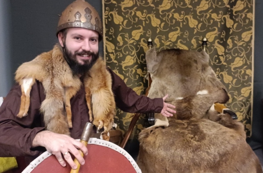 Wojciech Niemienionek - pracownik z Muzeum Pierwszych Piastów na Lednicy w stroju woja słowiańskiego w hełmie z tarczą i toporem